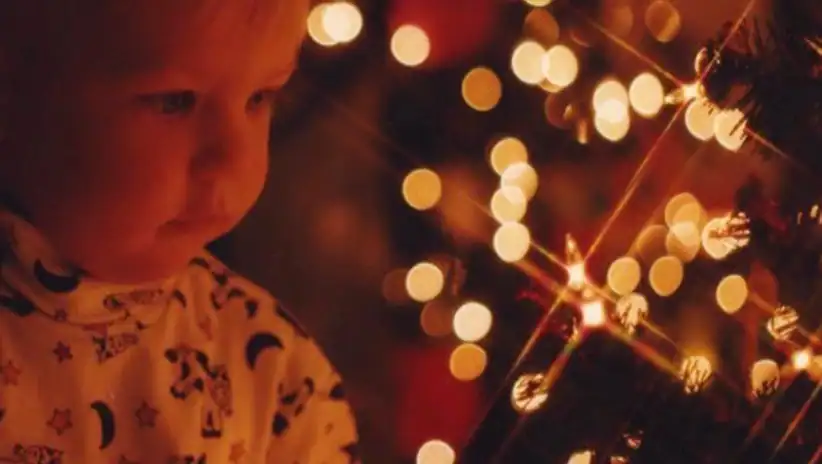 Child admiring festive holiday lights and sparklers, celebrating cultural traditions.