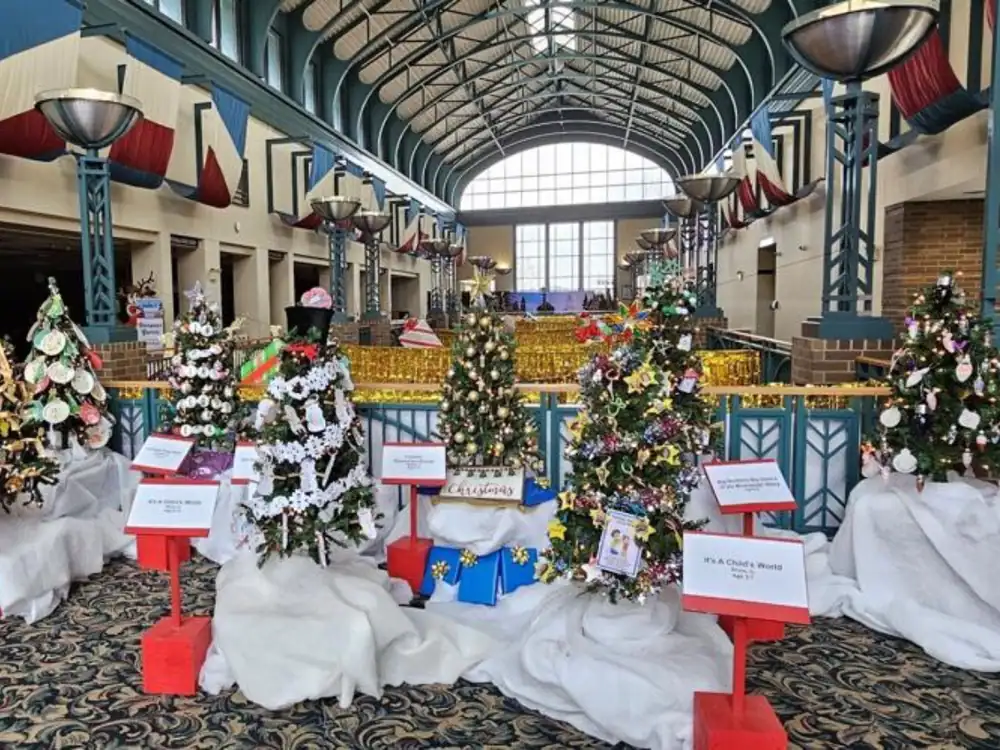 Christmas trees decorated with ornaments and lights in an indoor exhibition space.