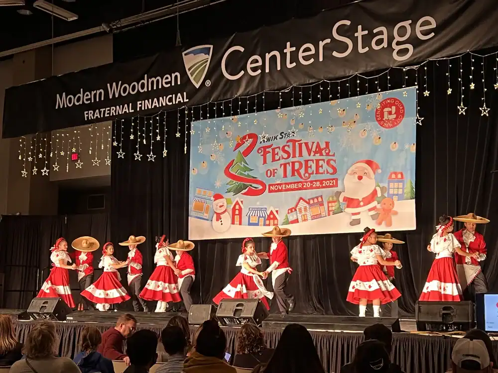 Festive dance performance at the Festival of Trees event on stage with holiday-themed costumes.