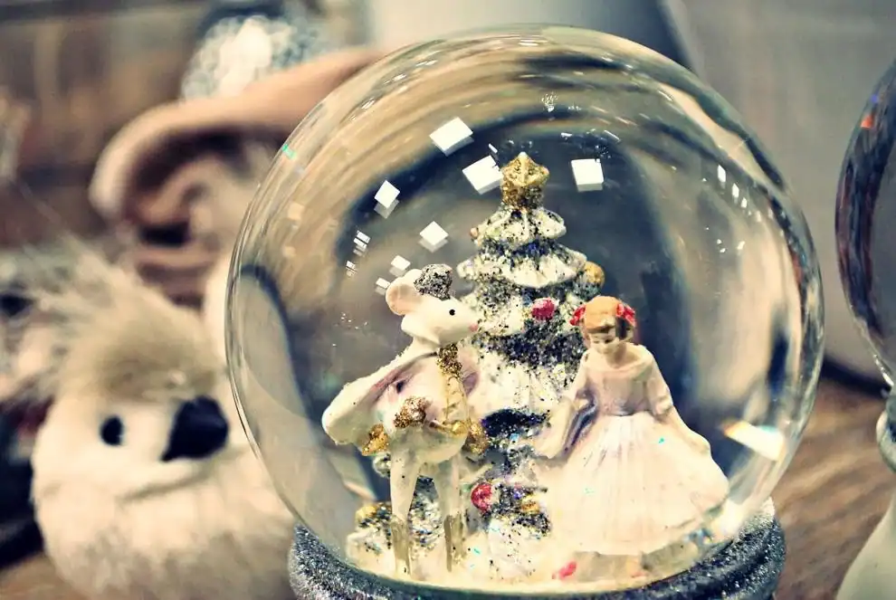 Christmas snow globe featuring miniature figures and a decorated tree inside a glass sphere.