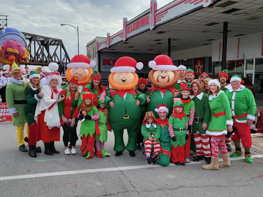 Group of people dressed in Christmas costumes with inflatable elves outside The Cultural Trust.