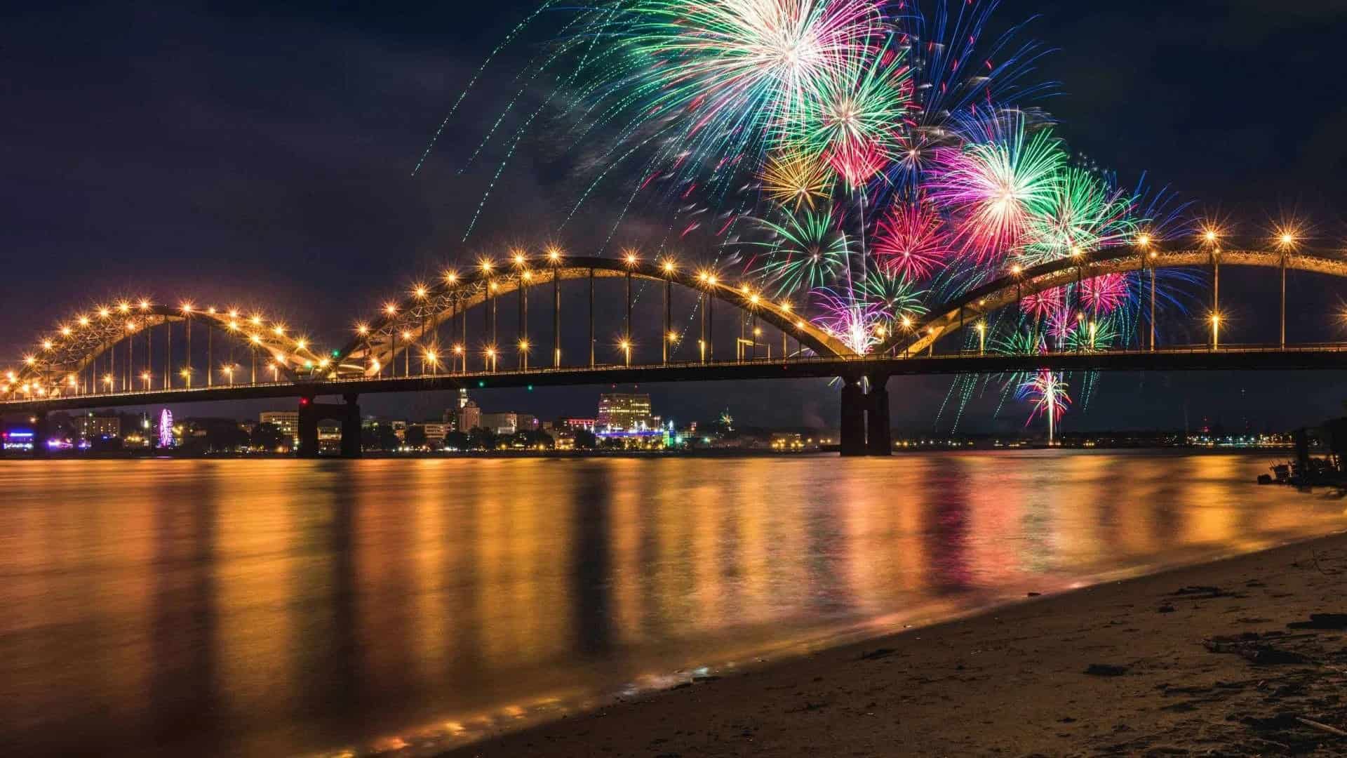 Fireworks display over a bridge at night, reflecting on the water, celebrating cultural events and c.