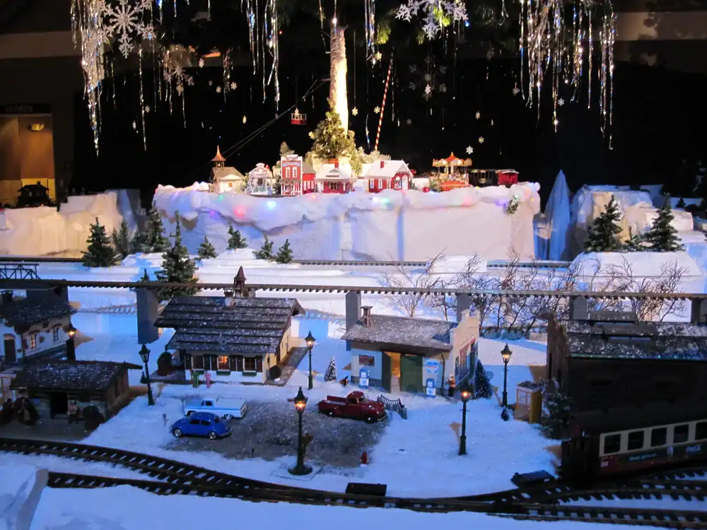 Festive Christmas village scene with miniature buildings, snow, and holiday decorations.