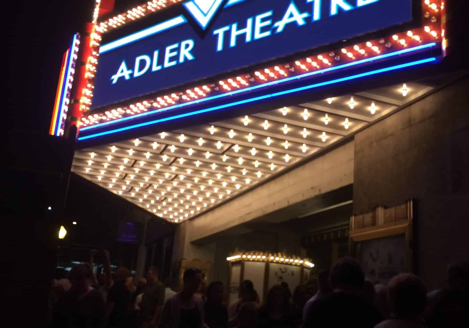 Adler Theatre marquee illuminated at night with crowd outside.
