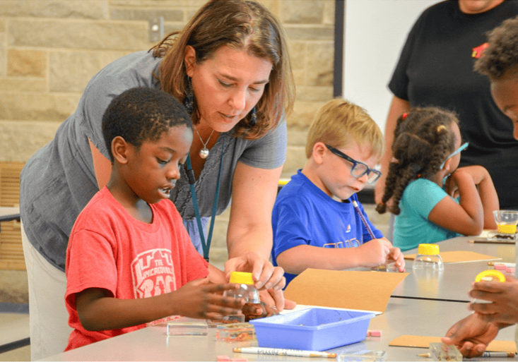 Children engaging in hands-on arts and crafts activity led by a facilitator.