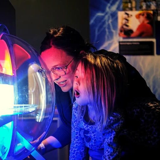 Child and adult engaging with colorful science display.