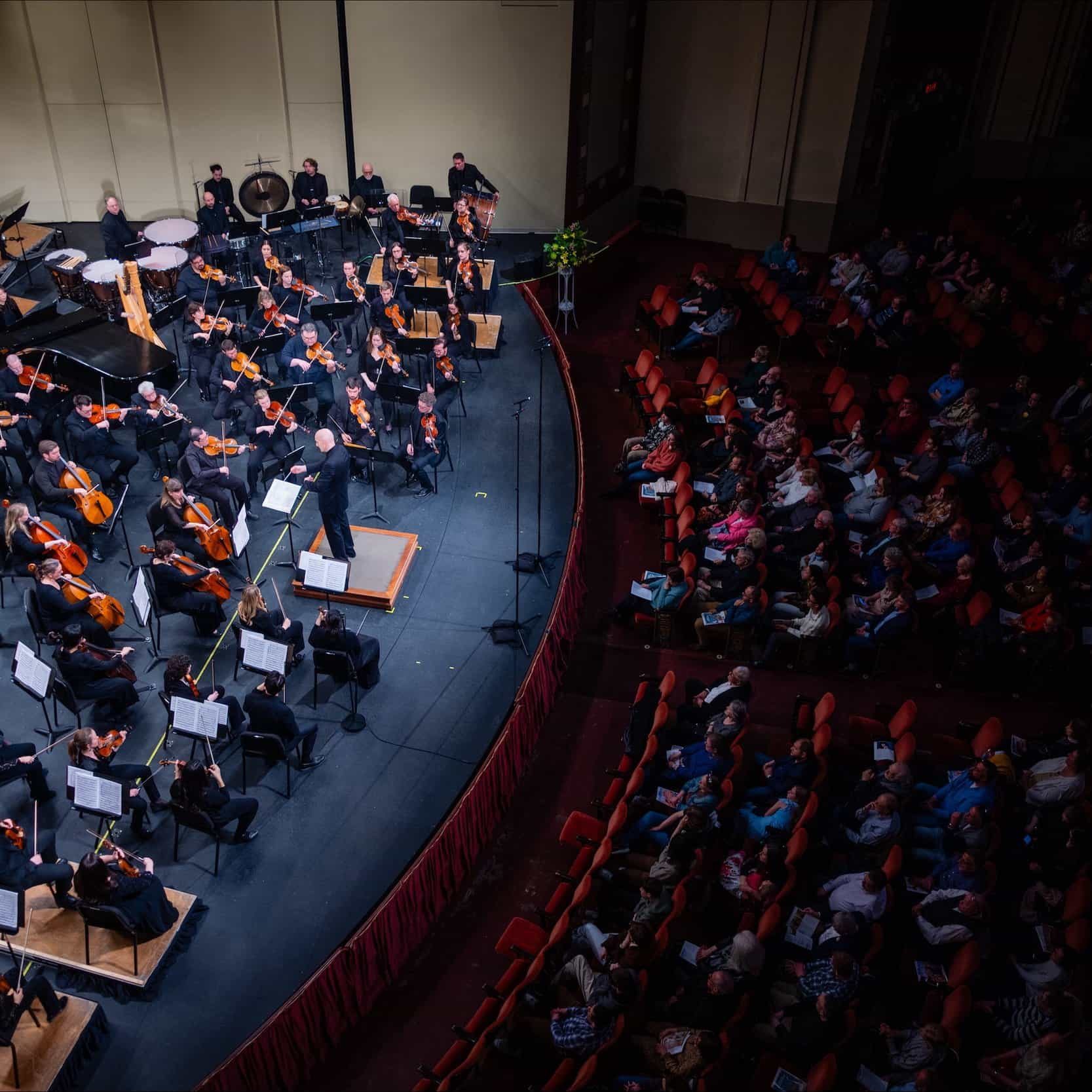 Orchestra performing on stage at The Cultural Trust event in a large auditorium.