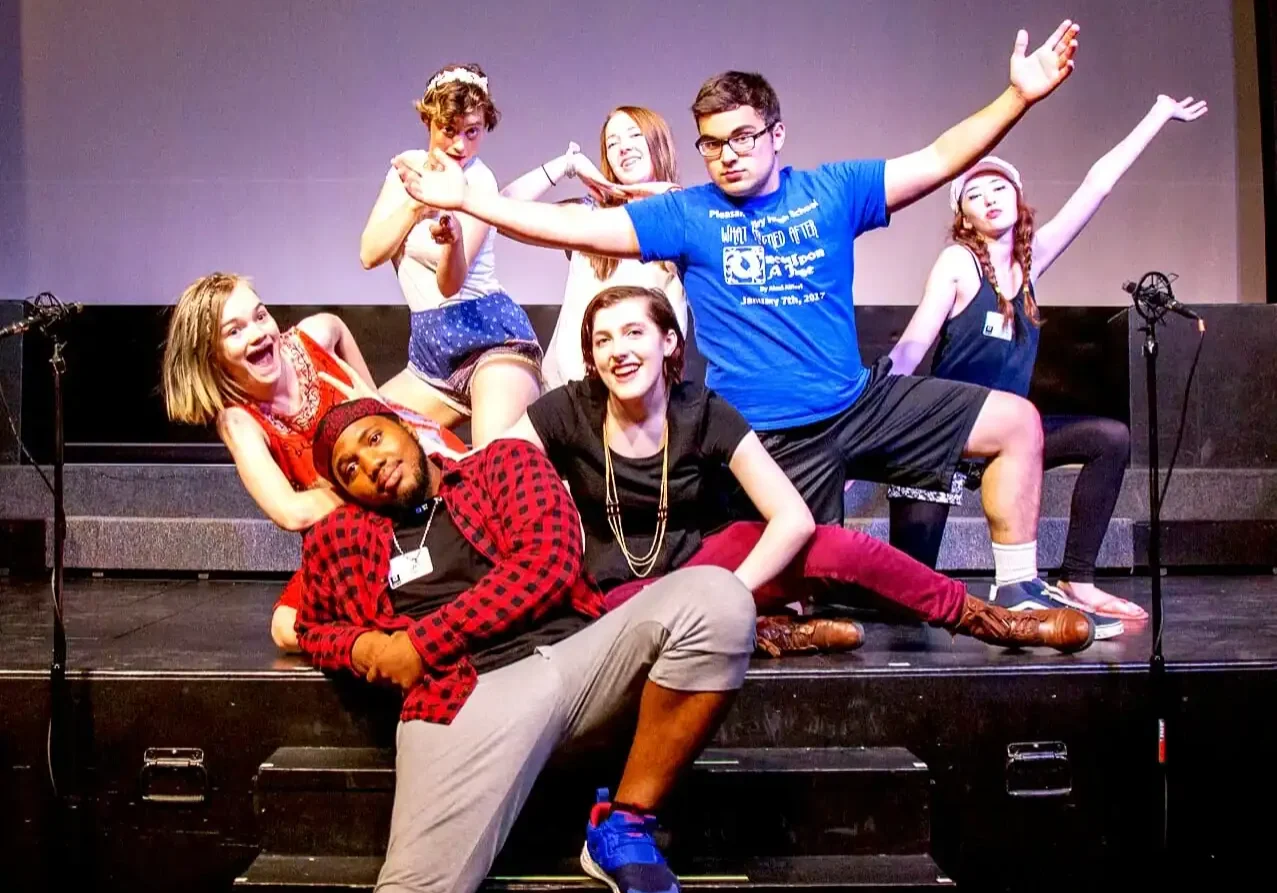 Diverse group of young performers on stage during a theatrical production.