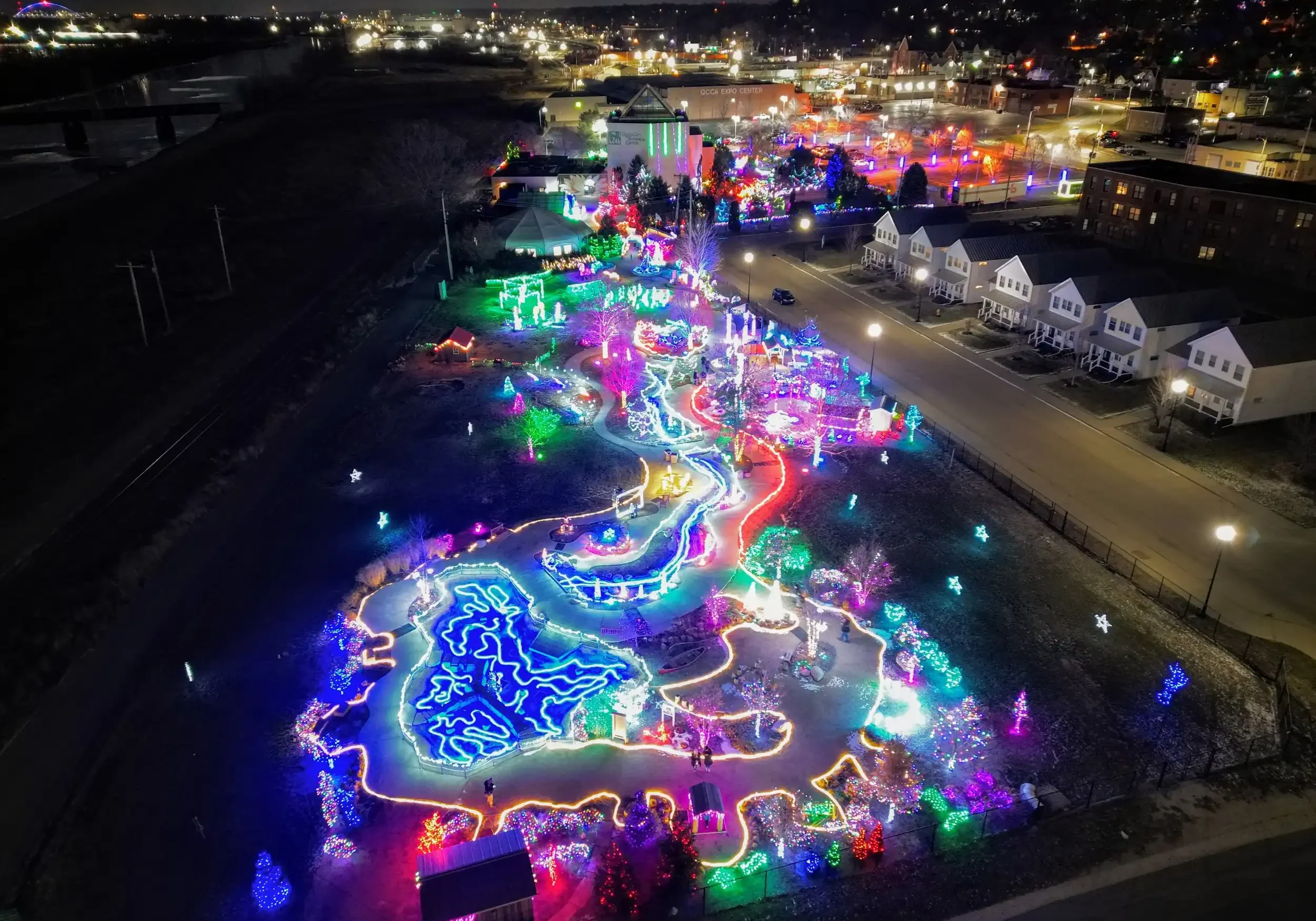 Colorful outdoor light display with illuminated pathways and artistic installations at night.